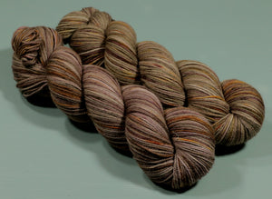
                  
                    Two skeins fo autumn coloured yarn with beautiful highlights of gold an orange against a rich brown background
                  
                